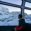 महामारी के दौरान स्विस एल्प्स में ट्रेन से यात्रा करता एक युवक.   