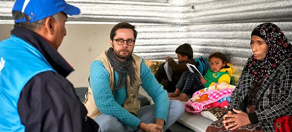 让-尼古拉斯在约旦阿兹拉克难民营的避难所与叙利亚难民瓦尔达和她的五个孩子交谈。