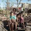 在热带气旋袭击马达加斯加过后，一名妇女和她两个年幼的女儿坐在她们被风暴摧毁的房子前。