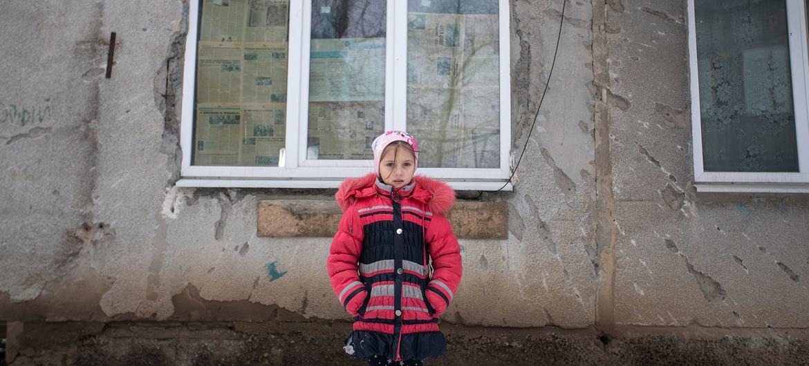 2022年2月6日，乌克兰东部一名9岁的女孩站在她家被冲突破坏的外墙前。