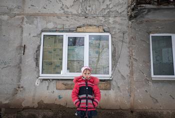 Menina em frente ao prédio danificado pelo conflito no leste da Ucrânia.
