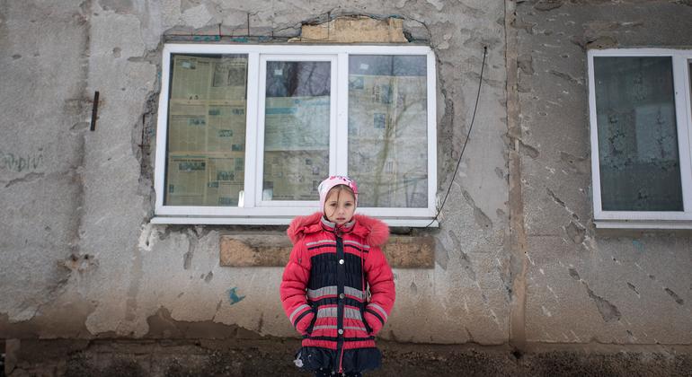 Menina em frente ao prédio danificado pelo conflito no leste da Ucrânia.