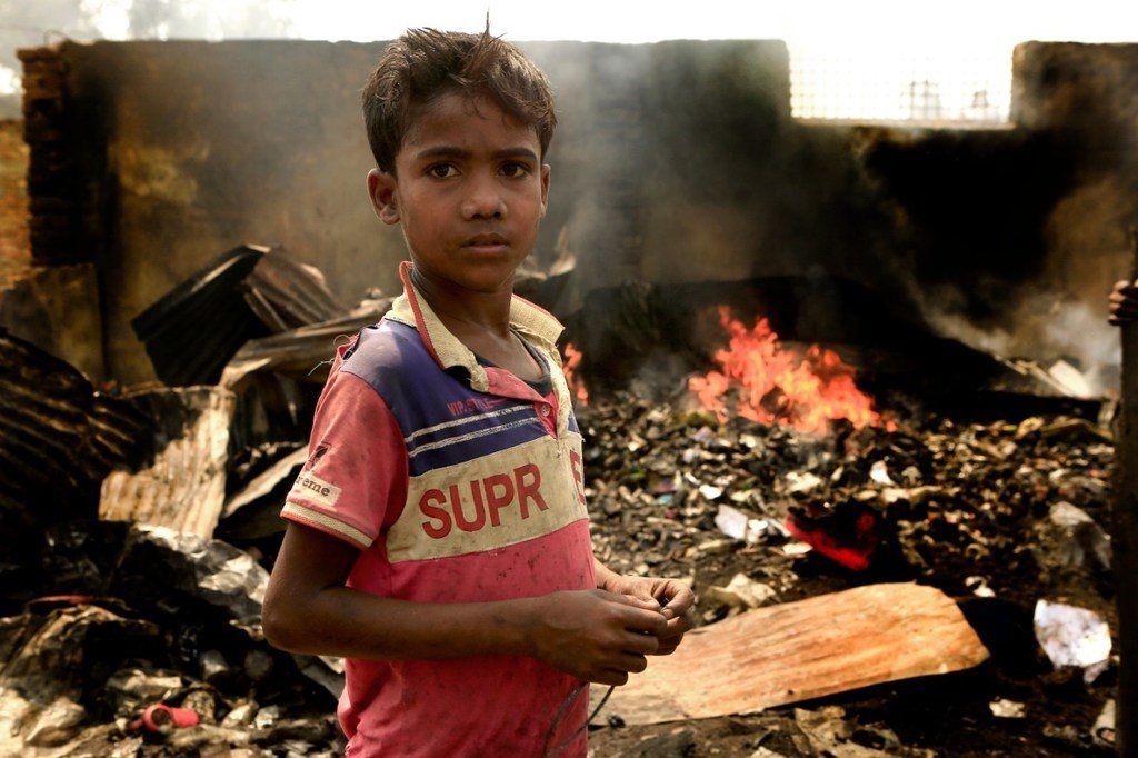3月23日，一个十岁的孩子站在孟加拉国南部库图帕隆难民营的废墟中。 大火在营地中肆虐了一天，在他身后，仍有火在燃烧。