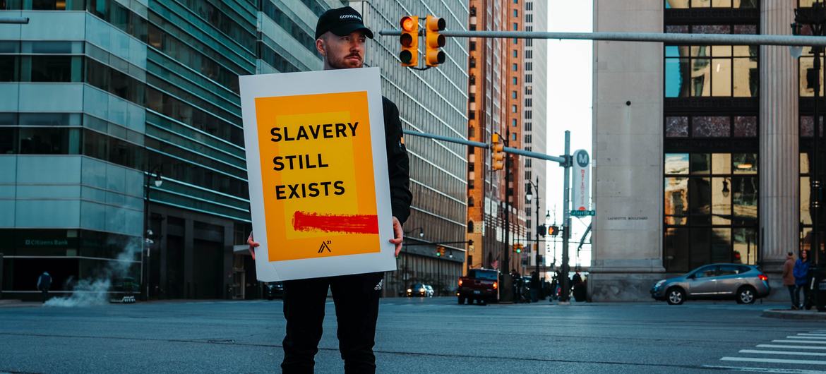 一名男子举着一块牌子，上面写着美国仍然存在奴隶制。
