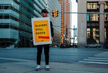 A man holds a sign reading 'Slavery still Exists' in the United States.