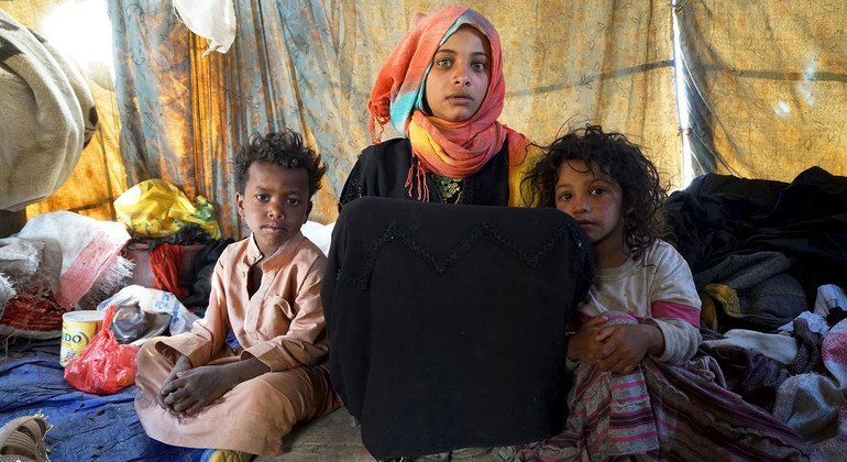 A 15-year-old girl sits with her two brothers in a tent in Khamir IDP settlement, Yemen, where they live with their five other siblings.