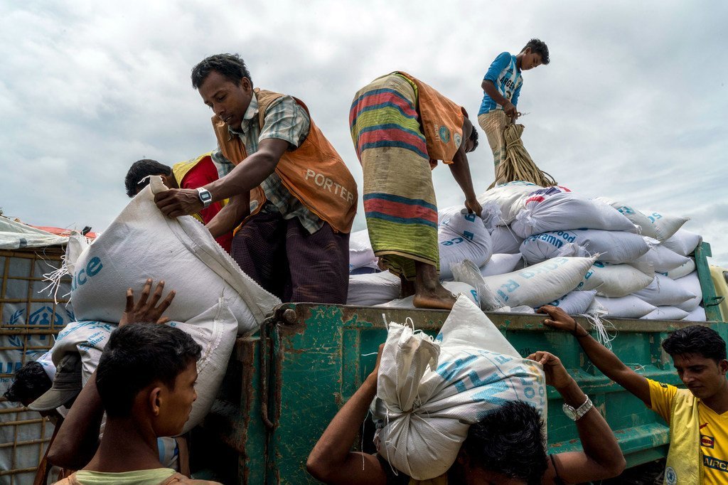 Des travailleurs réfugiés rohingyas distribuent des sacs de riz et de lentilles à un point de distribution du Programme alimentaire mondial (PAM) dans le camp de Kutupalong, au Bangladesh.
