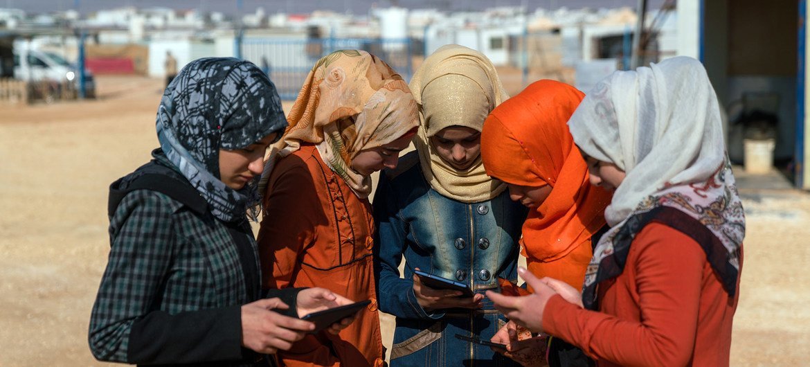 Niñas adolescentes usan teléfonos celulares y tabletas en el campamento de Za'atari para refugiados sirios (archivo).