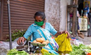 Esta vendedora callejera de verduras en la India porta una mascarilla para protegerse del COVID-19.