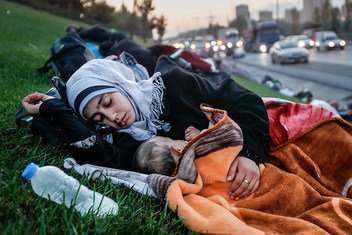 Una madre sin hogar duerme con su bebé en la hierba cercana a una autopista.