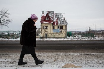 一名乌克兰女性走过一栋在冲突中被毁的房屋。