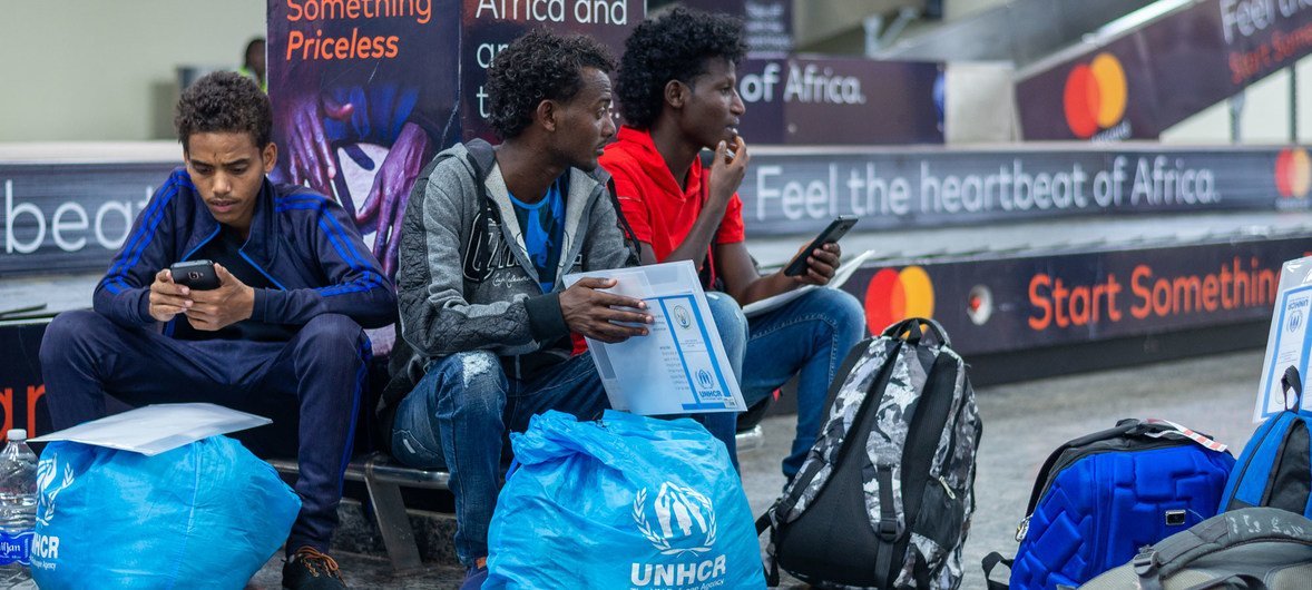 三名年轻的难民男子从利比亚被空运撤离后，在卢旺达基加利机场等候。