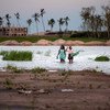 امرأة وطفل يسيران في منطقة غمرتها الفيضانات في مركز تيكا لإعادة التوطين، على بعد 80 كيلومترا من بيرا، موزمبيق، بعد أن شرد الإعصار المداري إلويز الآلاف.