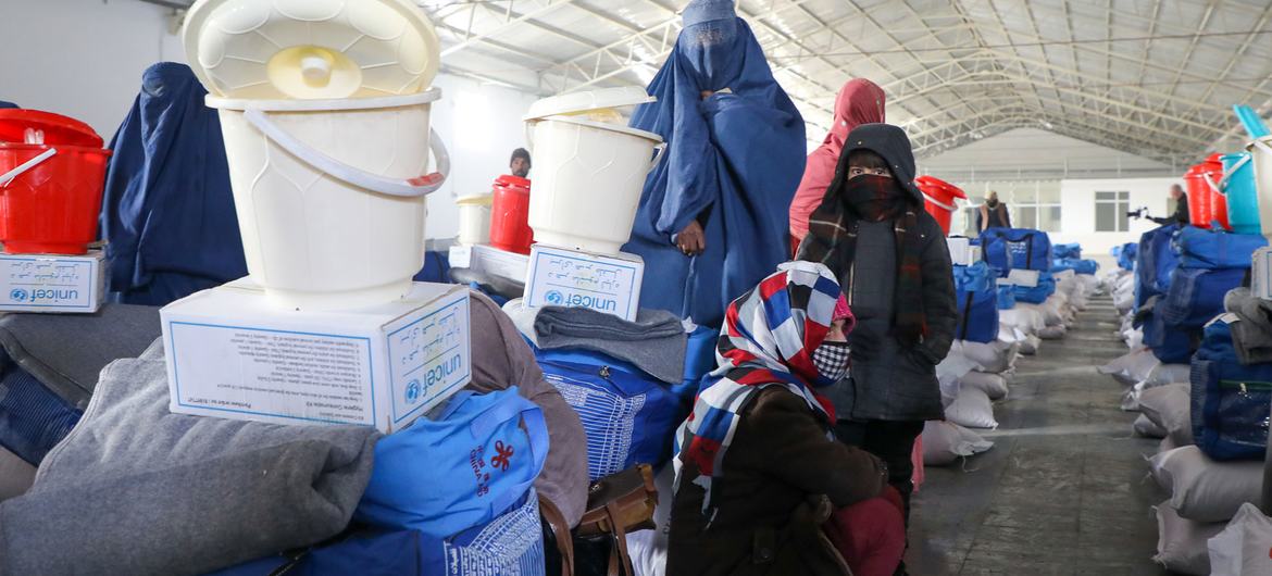 نساء وبناتهن يتلقين أطقم مستلزمات الشتاء من اليونيسف في أفغانستان. تشمل المجموعة الدقيق والأرز والبطانيات والملابس الدافئة والقماش المشمع ودلاء الماء.