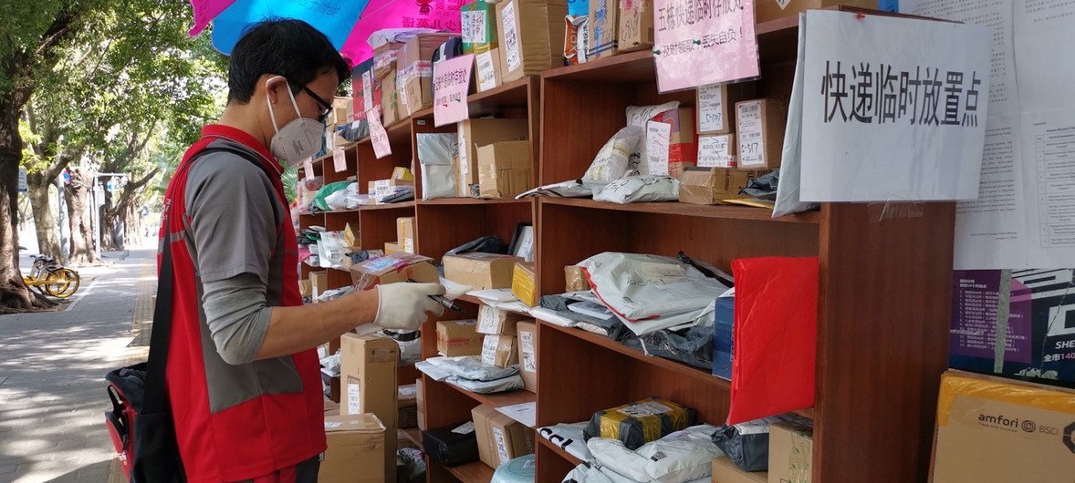 A messenger leaves packages at an outdoor drop-off location as he is not allowed to enter buildings during the coronavirus outbreak in China.