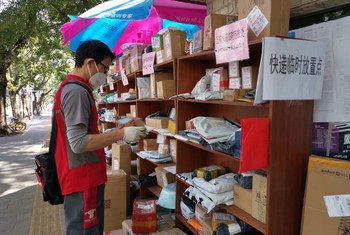A messenger leaves packages at an outdoor drop-off location as he is not allowed to enter buildings during the coronavirus outbreak in China.