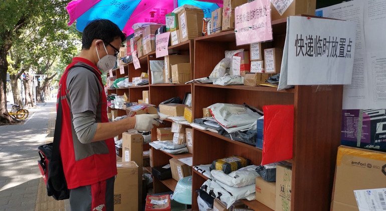 Un mensajero deja un paquete en un punto de recogida al no permitirse la entrada en los edificios durante el brote en China.