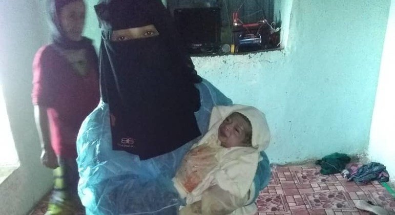في اليمن، قابلة تحمل طفلا ولد حديثا.