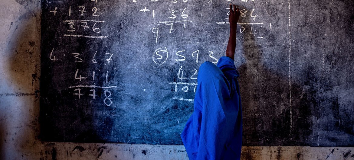 A young girl writes on a chalkboard at a primary school in Nigeria.