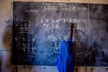 A young girl writes on a chalkboard at a primary school in Nigeria.