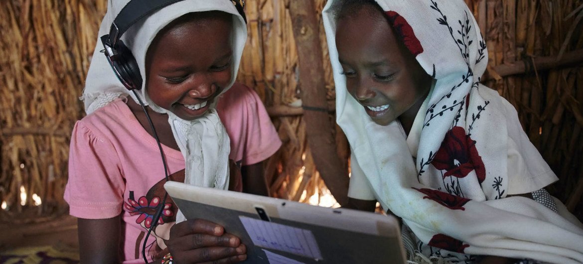 Crianças usam seu tablet em um centro de aprendizagem apoiado pelo Unicef em uma vila nos arredores de Kassala, no Sudão Oriental