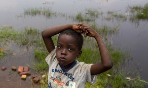 Mtoto akiwa amesimama karibu na pampu ya maji iliyozingirwa na maji ya mafuriko huko Gatumba nchini Burundi.