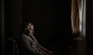 Elene, who lives in an IDP settlement in Karaleti, Georgia, looks at a photograph of her former home in South Ossetia.