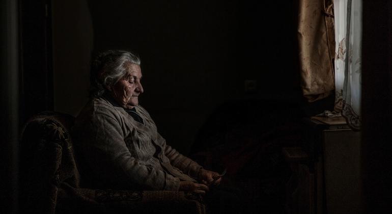 Elene, who lives in an IDP settlement in Karaleti, Georgia, looks at a photograph of her former home in South Ossetia.