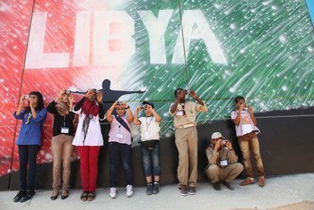 أطفال يشاركون في ورشة تصوير في ليبيا، يلتقطون الصور أمام جدارية في طرابلس. (من الأرشيف)