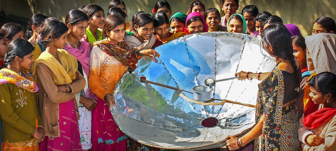 En la India, una mujer demuestra como cocinar con un reflector solar.