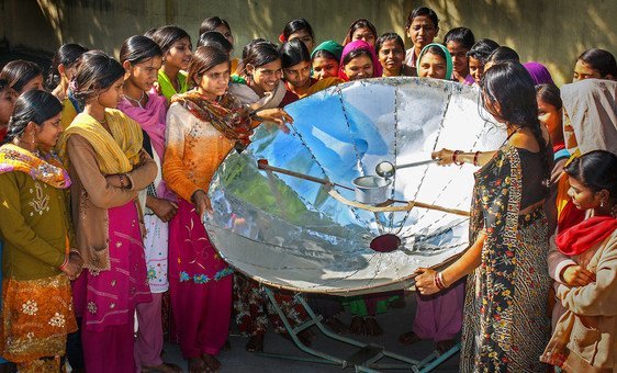 In India, a woman demonstrates how to use a solar dish for cooking.