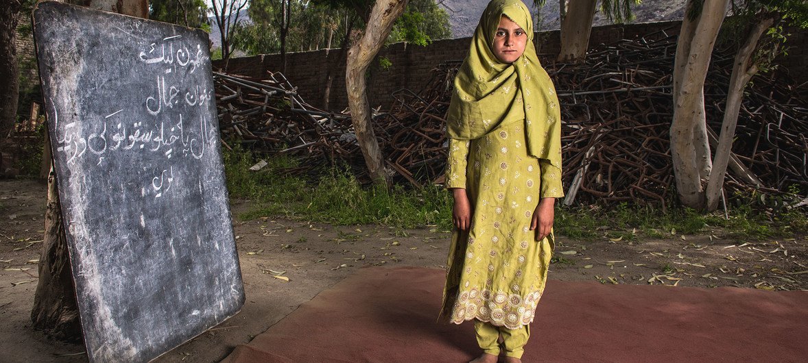 अफ़ग़ानिस्तान के एक गांव में बमबारी में क्षतिग्रस्त अपने स्कूल के बाहर खड़ी एक लड़की. 