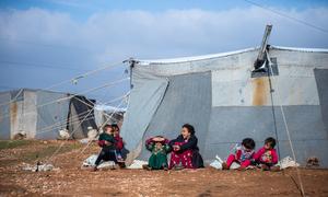 Niños sentados frente a la tienda de su familia en el campamento improvisado de Alzhouriyeh, en la zona rural del este de Homs (Siria).