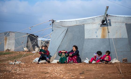 Niños sentados frente a la tienda de su familia en el campamento improvisado de Alzhouriyeh, en la zona rural del este de Homs (Siria).