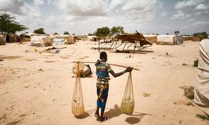 Une jeune femme porte de l'eau dans un camp de personnes déplacées dans la région de Tillaberi, au Niger.