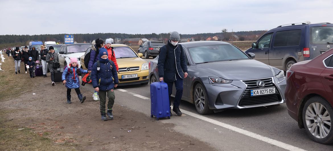  Alors que les opérations militaires se poursuivent, des personnes fuyant l'Ukraine marchent le long de véhicules faisant la queue pour passer la frontière entre l'Ukraine et la Pologne.