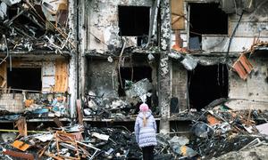2022 年 2 月 25 日，乌克兰基辅，一名女孩看着一座公寓楼前爆炸留下的残垣断壁，这所公寓楼在正在进行的军事行动中遭到严重破坏。