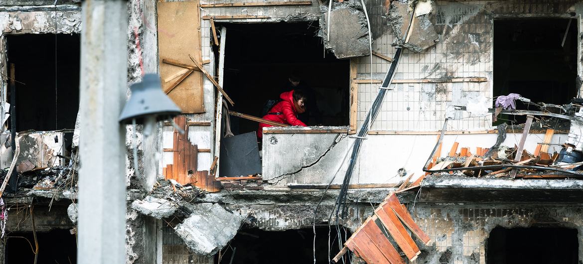 यूक्रेन की राजधानी कीयेफ़ में सैन्य अभियानों में बुरी तरह ध्वस्त इमारत मलबा हटाते हुए एक महिला.