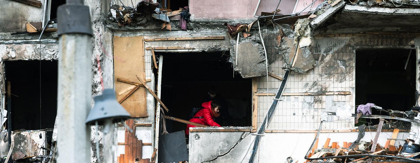 Une femme s'efforce de dégager les débris de son appartement après que le bâtiment ait été lourdement endommagé pendant les opérations militaires en cours à Kyïv, en Ukraine
