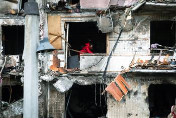 A woman works to clear debris in her apartment after the building was heavily damaged during ongoing military operations in Kyiv, Ukraine.