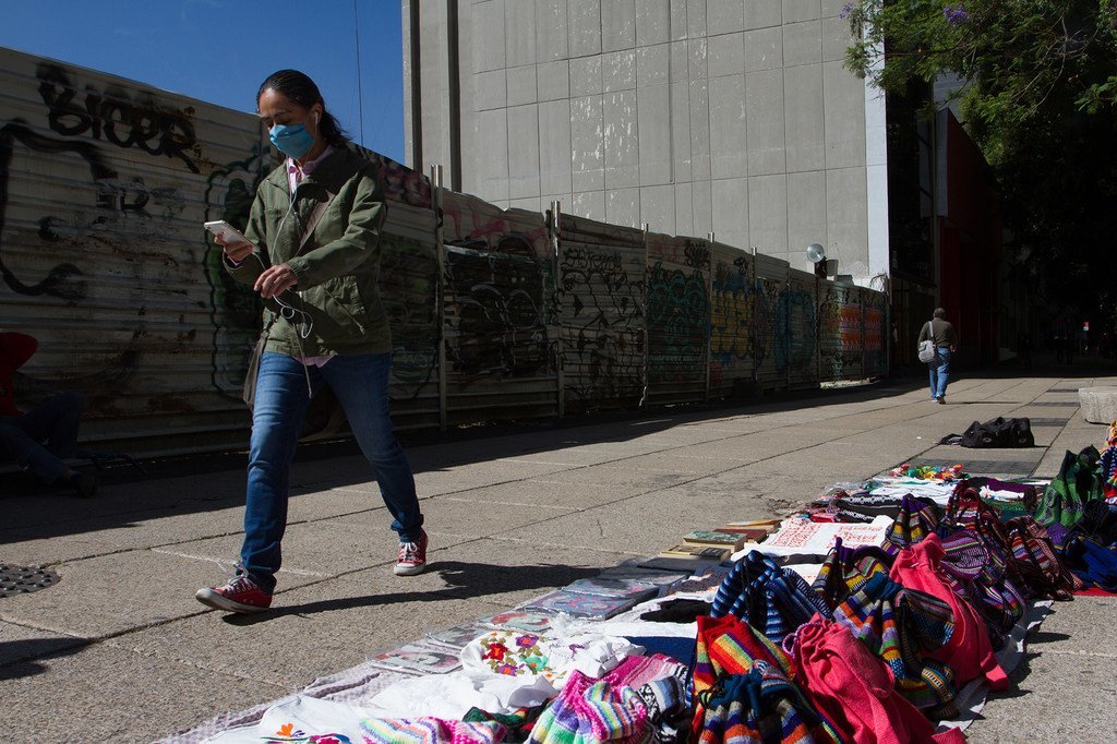 Un peatón camina mirando su teléfono móvil por las calles de la Ciudad de México durante la pandemia de COVID-19. 