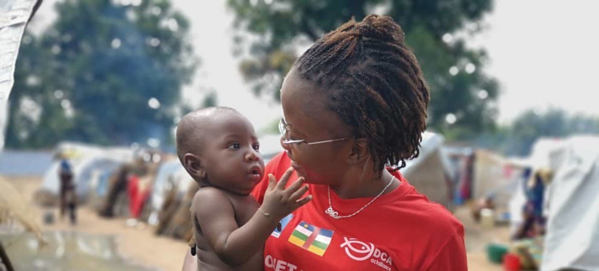Reporter et animatrice centrafricaine de Guira FM, Merveille Noella Mada-Yayoro tient un enfant lors d'un reportage dans le camp de déplacés de Birao.