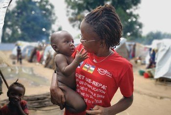 Reporter et animatrice centrafricaine de Guira FM, Merveille Noella Mada-Yayoro tient un enfant lors d'un reportage dans le camp de déplacés de Birao.