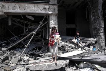 फ़लस्तीनी क्षेत्र ग़ाज़ा शहर में, एक लड़की और एक लड़का, अपने ध्वस्त घर के मलबे से सामान बीनते हुए.