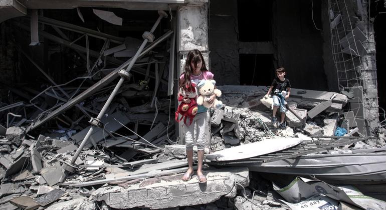 一名巴勒斯坦女孩和男孩从他们在加沙城受损的家中找寻物品。