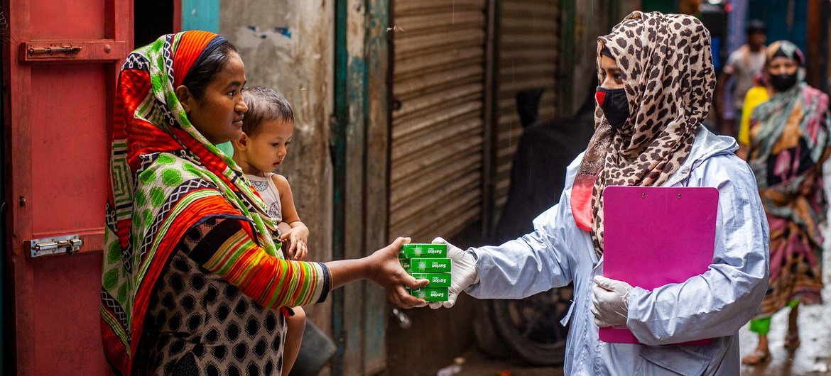 A health worker distributes hygiene supplies to a family in Dhaka, Bangladesh.