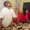 Mwanamume na watoto watatu wakifanya mazoezi pamoja kwenye zulia lenye muundo sebuleni.