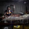 Criança de 11 anos resolve exercícios em casa em Nairóbi, Quênia. Ele não pode participar do aprendizado online porque sua família não tem um telefone celular.