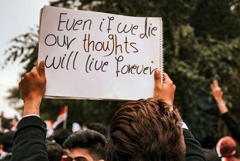 متظاهرون في ساحة التحرير في العاصمة العراقية بغداد، يرفعون لافتة باللغة الإنجليزية مكتوب عليها: حتى وإن نموت فإن أفكارنا ستعيش للأبد.