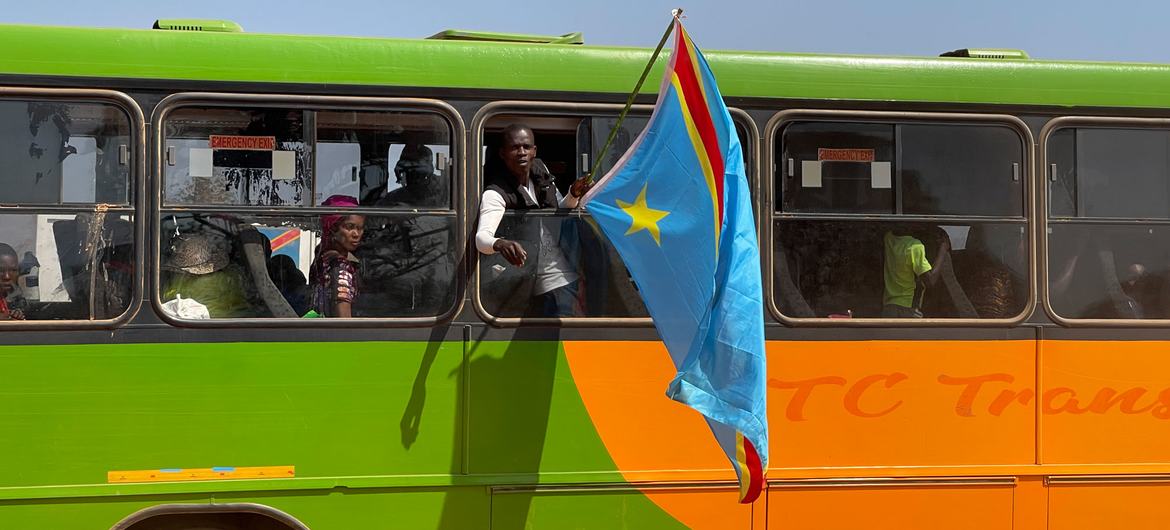 Des réfugiés congolais agitent un drapeau depuis le bus qui les ramènent chez eux à Pweto, dans la province du Haut Katanga, en République démoccratique du Congo.